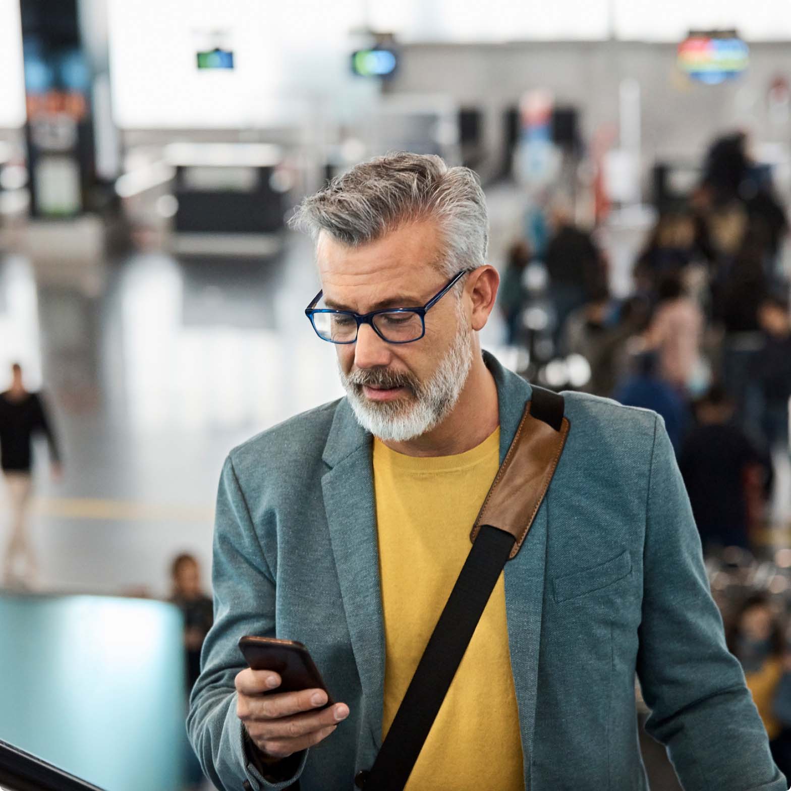 A man looking at his phone going up escalators at an airport