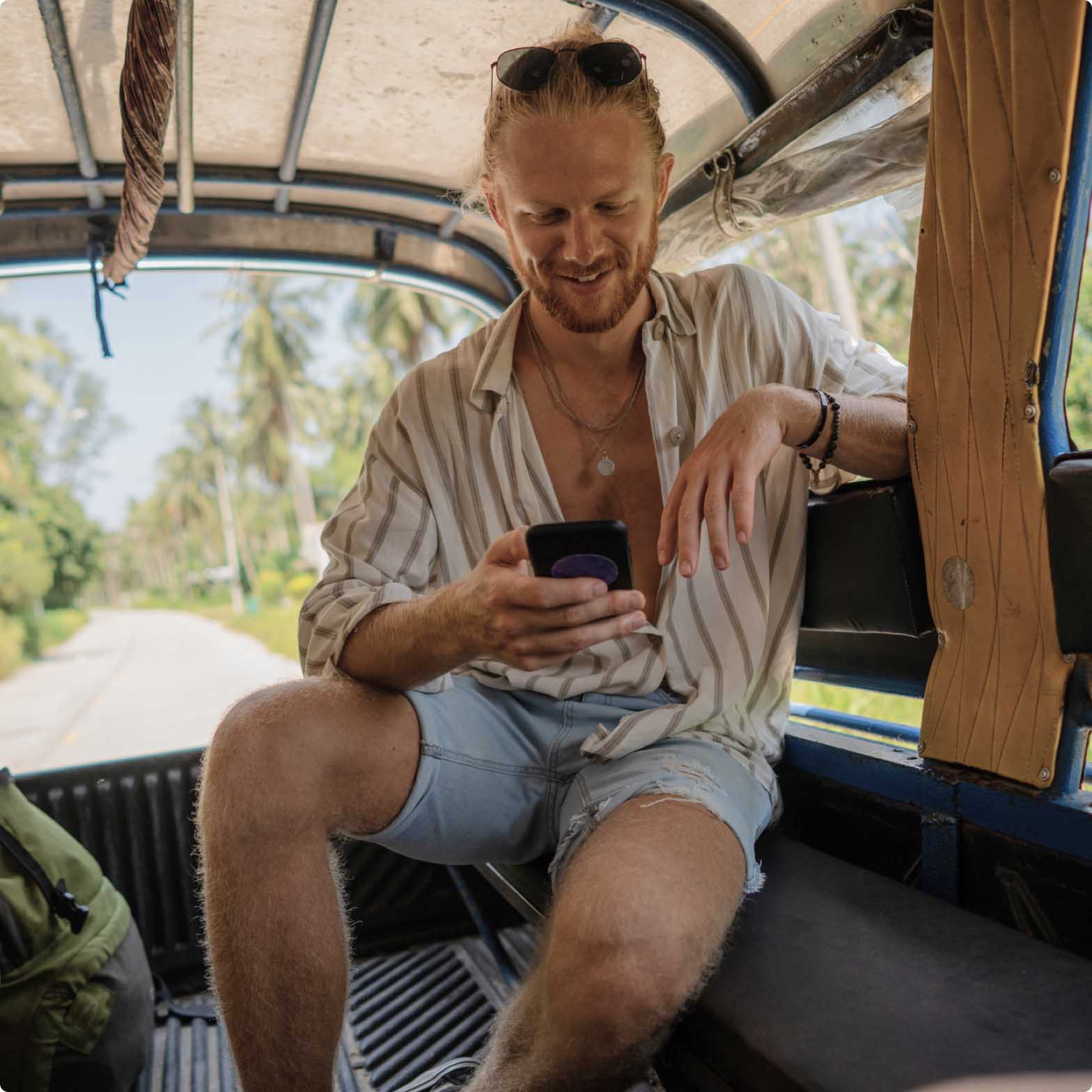 Advertising, man in the back of a safari van smiling at his phone